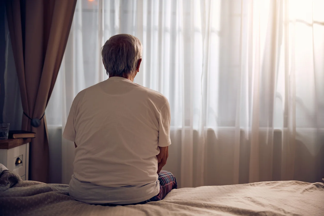 A senior looks sadly out the window, , representing nursing home abuse claims Clay Travis Law stands up for with compassion.