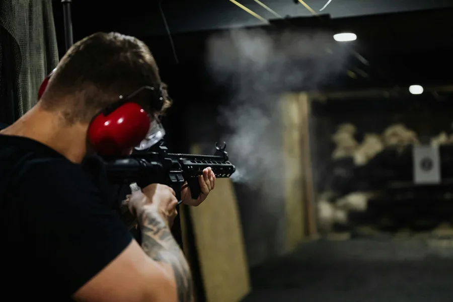 Man firing rifle at a gun range.